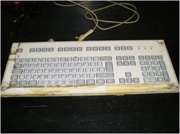 Office keyboard heavily contaminated with dust and debris before cleaning